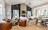 Luxurious open-concept living room with modern fireplace, chic leather chairs, an elegant wooden pool table, and abundant natural light.