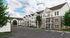Charming apartment complex with elegant balconies, stone accents, and lush landscaping on a sunny day.