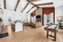 Chic apartment living area with vaulted wooden beam ceiling, elegant chandeliers, and cozy leather seating by a modern stone fireplace.
