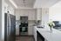 Modern kitchen with sleek stainless steel appliances, elegant white cabinetry, and a stylish countertop with fresh flower decor.