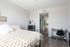 Bright and modern bedroom with chic decor, featuring a cozy bed, sleek wooden flooring, minimalistic workstation, and en-suite bathroom.