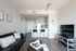 Modern apartment living area featuring a sleek leather couch, stylish decor, and a bright open kitchen with bar seating.