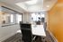 Contemporary meeting room with sleek black chairs, white table, and vibrant orange accent wall, offering a bright and modern workspace environment.