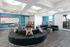 Modern communal living space with vibrant decor, circular seating, and bright blue accent walls, offering a stylish and inviting atmosphere.