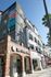 Modern apartment building offering premium urban living with retail shops like The Coffee Bean on-site, highlighted by sunny palm-lined walkways.