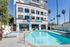 Inviting apartment complex with a luxurious pool area, modern architecture, and lush palm trees, perfect for relaxation and leisure.