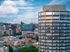 Modern high-rise apartment building with stunning cityscape views, featuring expansive windows and sleek architecture.