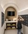Rendering of a modern mailroom with elegant arch ceiling, wooden accents, and ample mailbox space, featuring a stylish counter with decorative items.