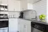 White cabinets in kitchen with large sink and updated appliances