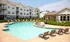The pool area at our apartments in Pembroke, featuring beach chairs, a shade structure, bushes, and a clubhouse.