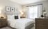 Model bedroom at our apartments in Pembroke, featuring carpeted floors, wood furniture, and a window.