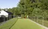 The dog park at our apartments in Pembroke, featuring a grassy area enclosed by a fence lined with gravel.