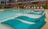 The pool area at our apartments for rent in Sandy Springs, featuring beach chairs, umbrellas, and seats in the pool.