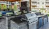 Outdoor lounge at our apartments for rent in Sandy Springs, featuring a grill station, outdoor couch, and a TV.
