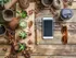 A cell phone on a wooden table near our apartments in Pembroke, MA, featuring succulents, sun glasses, and coffee.