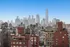 Photograph of the New York City skyline, featuring a view of brick buildings in the foreground and skyscrapers behind.