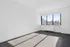 Empty room at our apartments in Midtown Manhattan, featuring wood grain floor paneling and a large window.