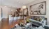 Model living room at our apartments for rent in Atlanta, featuring wood grain floor paneling and a view of the kitchen.
