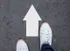 White Colored Arrow with a Person Wearing White Tennis Shoes