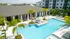 Pool courtyard at Marlowe Gateway featuring lounge chairs, palm trees, and a covered veranda with soft seating.