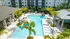 Pool courtyard at Marlowe Gateway with lounge seating, palm trees, a covered grilling area, and a covered veranda with soft seating