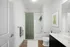 Modern bathroom with sleek design, featuring a green shower curtain, white subway tile, and elegant wood flooring.