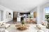 Bright open-concept apartment featuring a modern kitchen with dark cabinetry, spacious dining area, elegant wooden coffee table, and inviting seating with natural light pouring in.