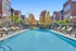 Inviting apartment complex with a sparkling blue swimming pool, ample lounge chairs, and vibrant autumn trees, surrounded by modern brick buildings.