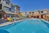 Vibrant community pool area with stylish lounge chairs, surrounded by modern townhomes under a clear blue sky.