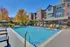 Inviting residential complex with a sparkling pool, modern lounge chairs, and vibrant autumn foliage, perfect for relaxation and community living.
