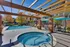Charming outdoor space featuring a sparkling swimming pool, cozy hot tub, and inviting patio seating with umbrella shades.