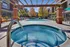 Inviting outdoor pool area with a hot tub, surrounded by comfortable lounge chairs and vibrant autumn trees, offering a perfect relaxation spot.