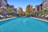 Inviting luxury apartment complex with a sparkling swimming pool, surrounded by sun loungers and lush trees, offering a serene and elegant lifestyle.