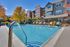 Inviting outdoor pool with colorful lounge chairs at a modern apartment complex, surrounded by lush autumn trees.