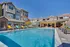 Elegant apartment complex with a dazzling outdoor pool, vibrant lounge chairs, and a stunning pergola-covered seating area.