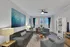 Inviting modern living room with stylish gray furniture, vibrant art pieces, and abundant natural light from large windows.