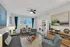 Bright and modern living room with chic decor, featuring cozy seating, a stylish wooden dining table, and vibrant artwork, ideal for both relaxation and entertaining.