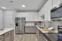 Elegant modern kitchen showcasing sleek stainless steel appliances, pristine white cabinetry, and stylish wood flooring, perfect for culinary creativity.