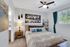 Elegant bedroom with cozy queen-sized bed, modern decor, and vibrant artwork, featuring a large window with lush green views.