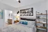 Inviting bedroom with chic decor, featuring a cozy bed with patterned linens, stylish wall art, and a sleek bookshelf, leading to a modern en-suite bathroom.