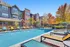 Inviting apartment view with a sparkling outdoor pool, vibrant lounge chairs, and colorful autumn foliage, promising a relaxing lifestyle.