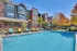 Charming apartment complex with a sparkling outdoor pool, colorful lounge chairs, and beautifully landscaped surroundings.