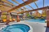 Inviting outdoor pool area with a relaxing hot tub and stylish pergola, surrounded by comfortable lounge chairs and vibrant autumn foliage.