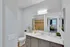 Modern bathroom with elegant vanity, large mirror, and view into a cozy bedroom. Features neutral colors and stylish decor.