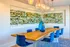 Modern dining area with vibrant blue chairs and natural wood table, featuring a unique wall-mounted plant display and elegant pendant lighting.