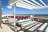 Luxury rooftop terrace with modern loungers, vibrant flower planters, and stunning ocean views under a sleek pergola.