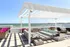 Luxurious rooftop terrace with modern pergola, ocean view, and chic outdoor seating, adorned with vibrant flowers.