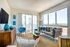 Chic living room with modern decor, featuring large windows offering stunning ocean views and hardwood- style plank flooring