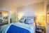 Cozy bedroom showcasing a plush bed with blue accents, soft lighting, and elegant decor for a relaxing ambiance.