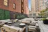 Chic urban patio featuring elegant wooden seating, lush greenery, and a vibrant city backdrop.